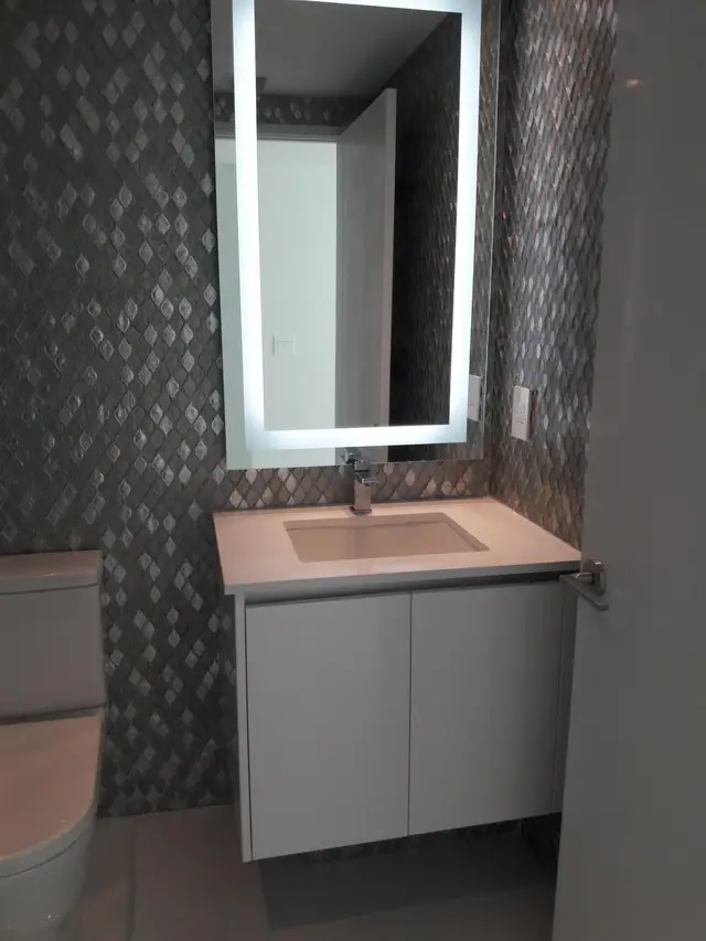 Modern bathroom shower and lit vanity mirror